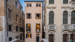 A narrow street with buildings featuring traditional architecture, including balconies and arched windows. - Lion Palace Deluxe R&R (Venecia)