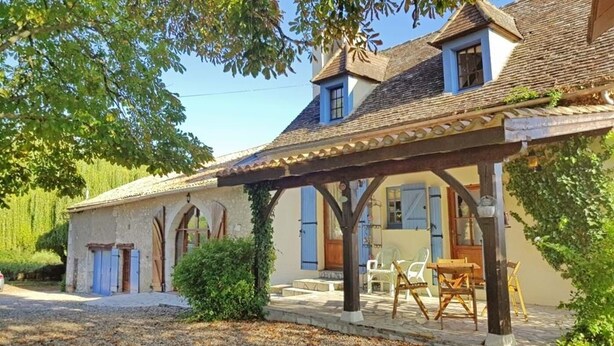 Une maison de campagne avec une véranda, des murs en pierre et un petit jardin.