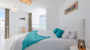 Un dormitorio moderno con una cama grande, un balcón y vista a la ciudad.