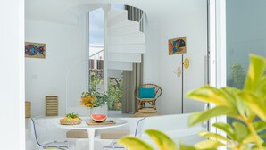 Habitación moderna y bien iluminada, con vistas despejadas al exterior, una escalera blanca y un sillón de mimbre.