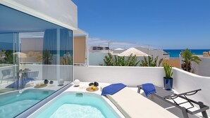 Eine Dachterrasse mit Whirlpool, Liegestühlen und Meerblick.