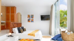 Une chambre d’hôtel moderne équipée d’un lit, d’une télévision, d’un panier de fruits et d’une grande fenêtre avec des rideaux.