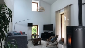 Uma sala de estar com sofá, televisão, lareira e janela com cortinas.