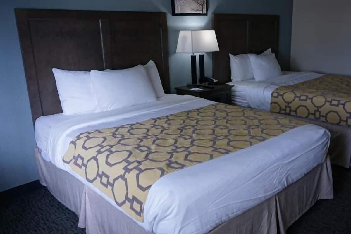 Een hotelkamer met twee bedden, een nachtkastje, een lamp en een lijst met een afbeelding aan de muur.