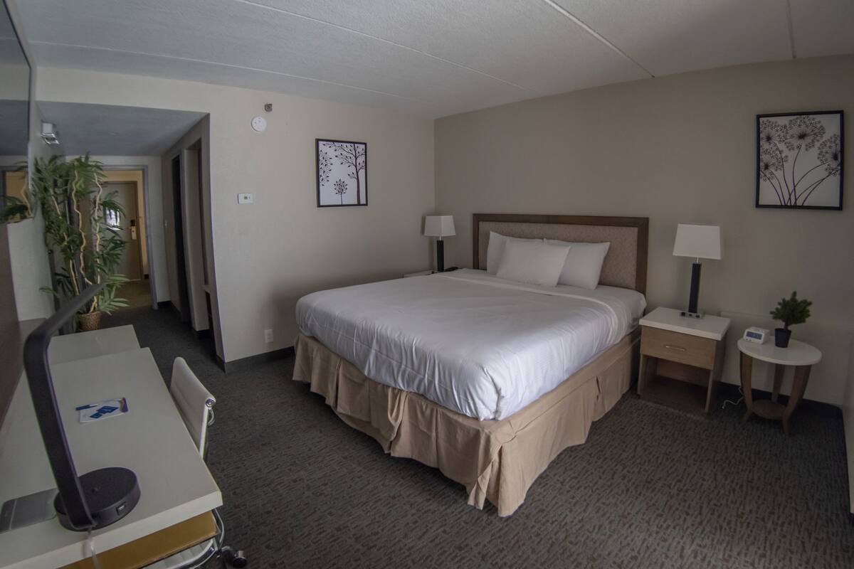 Een hotelkamer met een bed, nachtkastjes, een bureau en een stoel.