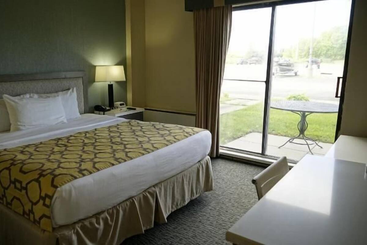 Een hotelkamer met een bed, een bureau, een lamp en uitzicht op de omgeving.