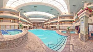Una piscina interior con varios niveles de balcones, una zona de piscina central y suelo de baldosas de piedra.