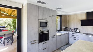 A modern kitchen with grey cabinetry, a built-in oven, microwave, and a coffee maker.