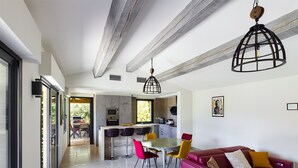 A modern kitchen with a dining area, red and yellow chairs, and a red sofa.
