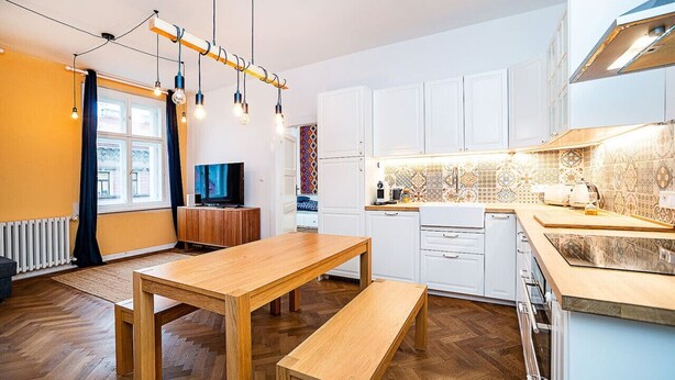 A modern kitchen with white cabinets, a wooden dining table, and a bench. - Elegant, modern, 2-bed flat by Museum of Prague (Prague)
