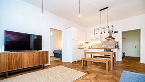 A modern living room with a flat-screen TV, wooden furniture, and a herringbone-patterned floor. - Elegant, modern, 2-bed flat by Museum of Prague (Prague)