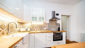 A modern kitchen with white cabinets, a patterned backsplash, and a wooden countertop. - Elegant, modern, 2-bed flat by Museum of Prague (Prague)