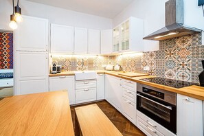 A modern kitchen with white cabinets, a wooden countertop, and patterned backsplash tiles.