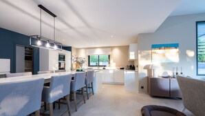 A modern kitchen with a dining area, a built-in island, and a cozy seating area with a sofa and a small rug.