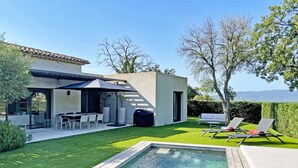 A modern outdoor patio with a pool, seating area, and a view of the mountains.