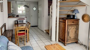 Un espace de vie compact comprenant un coin repas, une kitchenette et un escalier menant à un niveau supérieur.