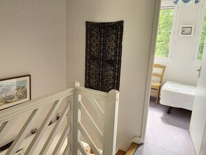 A staircase with a white railing leading to a room with a bed and a chair. - Duplex with Terrace near Beach and Shops in Saint-Pair-sur-Mer (Saint-Pair-sur-Mer)