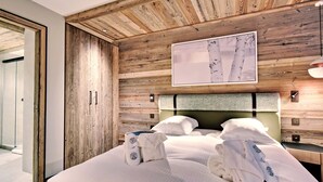 A bedroom with a wooden ceiling, a bed with white linens, and a framed picture above the bed.