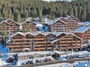 Un conjunto de cabañas de madera con varios balcones, rodeadas de nieve y un denso bosque.