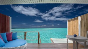 A wooden deck with a white cushioned seating area and a small table, overlooking turquoise waters. - Cora Cora Maldives-Premium All-Inclusive (Maamigili Island)