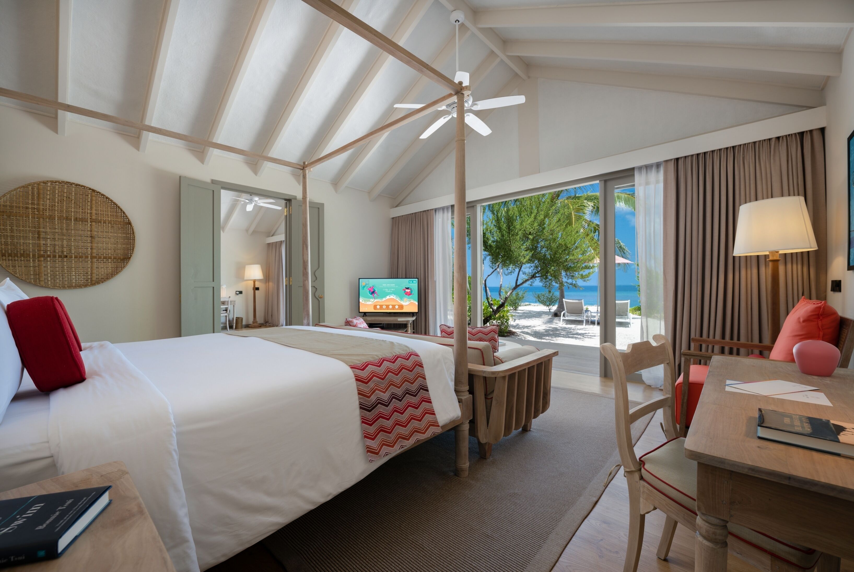 Une chambre d’hôtel équipée d’un lit, d’un bureau, d’une chaise, d’une télévision et offrant une vue sur la plage.