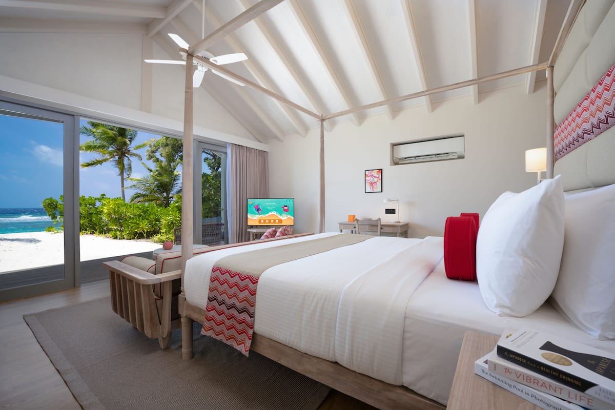 A bedroom with a large bed, a TV, and a view of the beach.