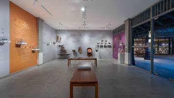 Un intérieur comprenant une longue table en bois, des murs blancs et divers objets d’art exposés.