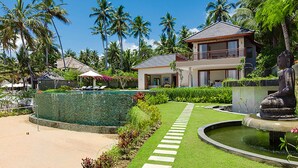 Ein Resort mit Swimmingpool, Palmen und einer Buddha-Statue.