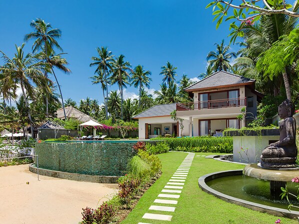 A resort with a swimming pool, palm trees, and a Buddha statue. - Villa Tirta Nila by Elite Havens (Manggis)