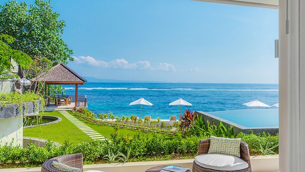 Ein Balkon mit Korbmöbeln, eine kleine Laube und Blick auf das Meer.