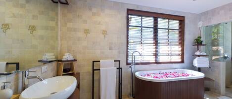 A modern bathroom with a large oval bathtub, a freestanding sink, and a walk-in shower.