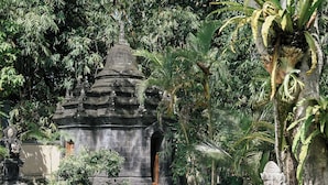 A temple-like structure surrounded by lush greenery and stone statues. - Villa San (Ubud)