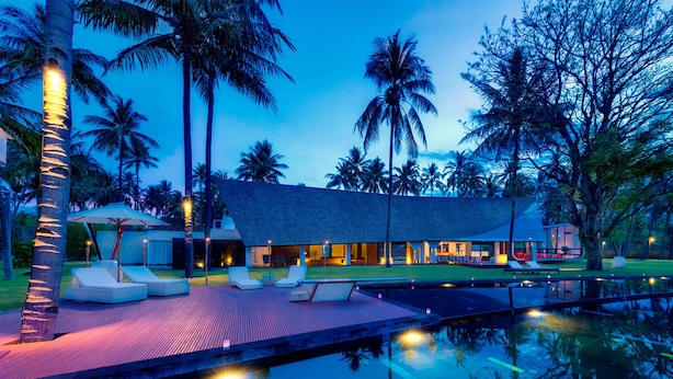 Un resort con piscina, lettini e palme.