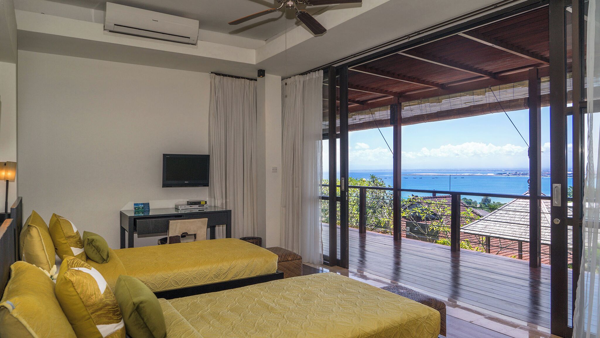 Une chambre d’hôtel avec deux lits, une télévision et un balcon donnant sur l’océan.