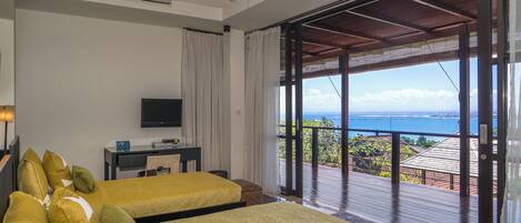 Une chambre d’hôtel avec deux lits, une télévision et un balcon donnant sur l’océan.