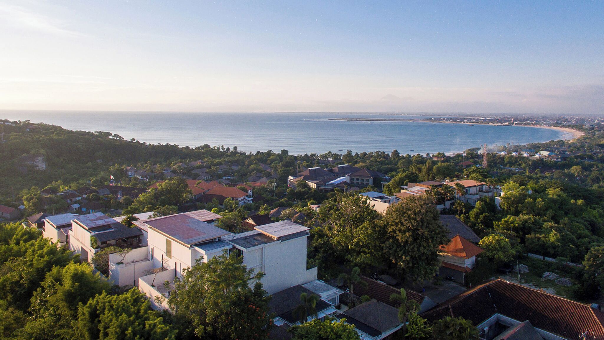 Zona residencial a la costa, amb cases, arbres i vista al mar.