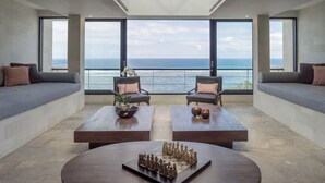 A spacious room with a large window overlooking the ocean, two sofas, two armchairs, and a chessboard on a central table. - Grand Cliff Nusa Dua (Nusa Dua)