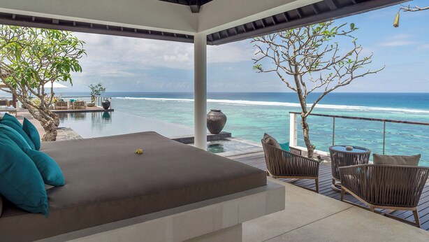 A balcony with a view of the ocean, a sofa with teal cushions, and a small table with chairs. - Grand Cliff Nusa Dua (Nusa Dua)