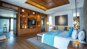 Habitación de hotel moderna con una cama grande, televisión, estanterías de madera con objetos decorativos y un cuadro abstracto de gran tamaño en la pared.