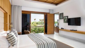 Un dormitorio moderno con una cama grande, televisión y balcón con vistas a zonas verdes.