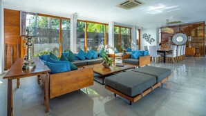 Un salón amplio con un conjunto de sofá de madera, una mesa de centro y un comedor con una mesa y sillas de madera.