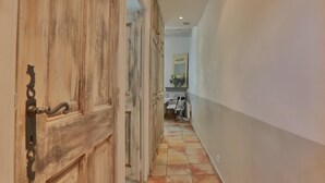 A hallway with a rustic wooden door, a tiled floor, and a white wall with a mirror and a vase of flowers. - Apartement Enjoy the Experience Gordes (Gordes)