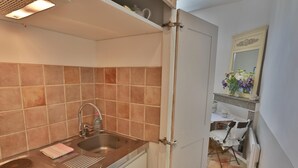 A kitchen with a stainless steel sink, a white cabinet, and a tiled backsplash. - Apartement Enjoy the Experience Gordes (Gordes)