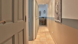 Um corredor com uma sala de jantar no final, com uma mesa e cadeiras.