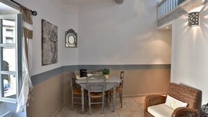 Uma área de refeições com mesa, cadeiras, um sofá de vime e uma escada.