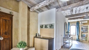 A compact kitchen with a wooden cabinet, a small sink, and a countertop. There is a potted plant on a table, and a mirror on the wall. - Apartement Like a Local Gordes (Gordes)