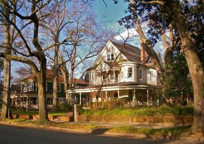 A two-story house with a porch, surrounded by trees.