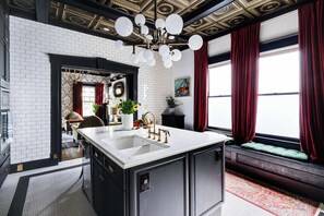 A kitchen with a white island, black cabinets, and a decorative ceiling.