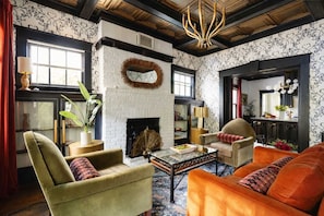 A living room with a fireplace, a round mirror, and a chandelier.