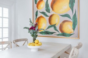 A dining area with a white table, a bowl of lemons, and a painting of lemons on the wall. - Aix-EN-Atlanta (Atlanta)